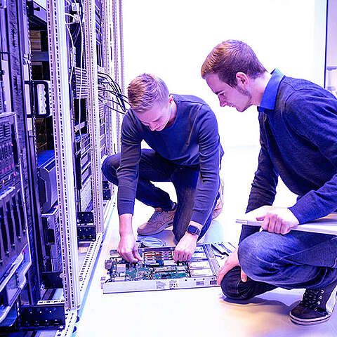 Das Portfolio des Q-FOX® Zwei Mitarbeiter, die vor einem Serverschrank knien und an der Technik arbeiten