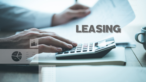 Nahaufnahme einer Person, die einen Taschenrechner mit Finanzunterlagen auf einem Schreibtisch benutzt. Das Wort "LEASING" ist in fetten Buchstaben quer über das Bild zu lesen. Eine Kaffeetasse und Tabellen sind im Hintergrund schwach zu erkennen.