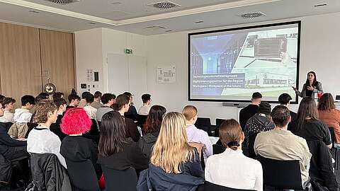 Eine Schulklasse hört sich einen Vortrag der Geschäftsführerin Eva Neu zum Thema Ausbildung an