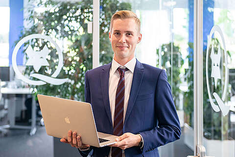 Auszubildender Kaufmann für E-Commerce mit einem Laptop in der Hand