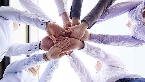 Mehrere Hände kommen in der Mitte zusammen