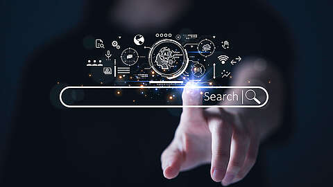 Eine Hand berührt eine virtuelle Suchleiste mit dem Wort „Search“ und einem Lupensymbol. Über der Leiste befinden sich digitale Symbole zu künstlicher Intelligenz und Technologie auf dunklem Hintergrund.