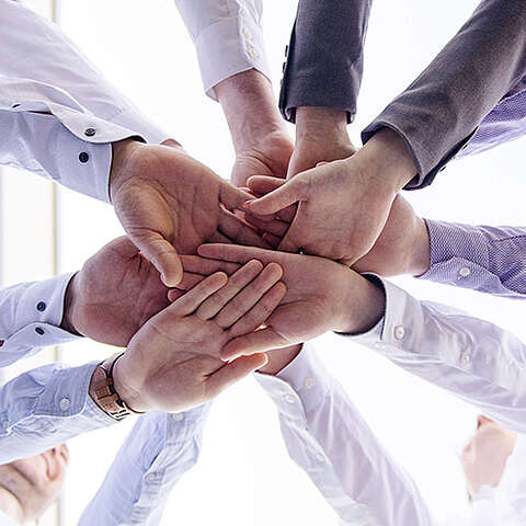 Partner der Q-FOX® Gruppe Personengruppe, die die Hände in der Mitte zusammenhält