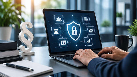 Eine Person tippt auf einem Laptop, auf dessen Bildschirm Symbole zum Thema Cybersicherheit und Datenschutz zu sehen sind, darunter ein Schild mit einem Schloss, ein Netzwerk-, ein E-Mail- und ein Cloud-Symbol, in einer modernen Büroumgebung, in die Sonnenlicht durch die Fenster fällt.