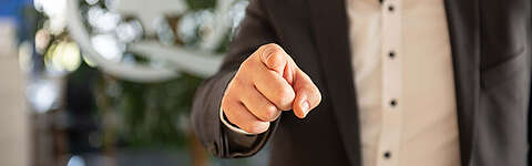 Aufzeigender Finger einer Person im Anzug