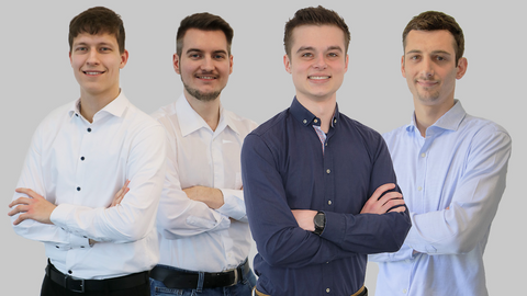 Vier Werkstudenten im Hemd, mit verschränkten Armen, lächeln in die Kamera.