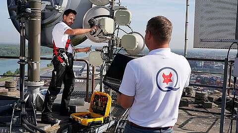 Ein Q-FOX® Mitarbeiter montiert eine Richtfunkantenne