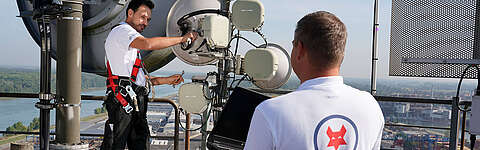 Ein Q-FOX® Mitarbeiter montiert eine Richtfunkantenne