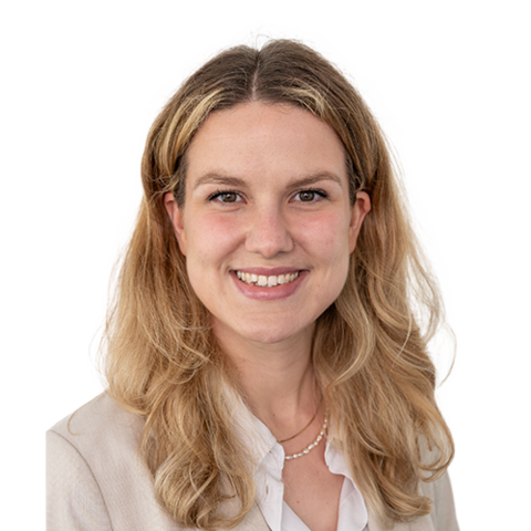 Eine lächelnde Frau mit schulterlangen blonden Haaren, die ein weißes Hemd und einen hellen Blazer trägt.
