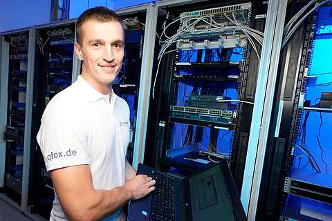 Auszubildender Fachinformatiker für Systemintegration hält Laptop im Serverraum