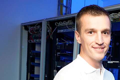 Auszubildender Fachinformatiker für Systemintegration hält Laptop im Serverraum